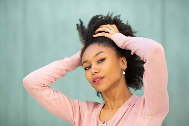 Закрыть портрет красоты молодая черная женщина с руками за головой на зеленом фоне
  - Фото, изображение