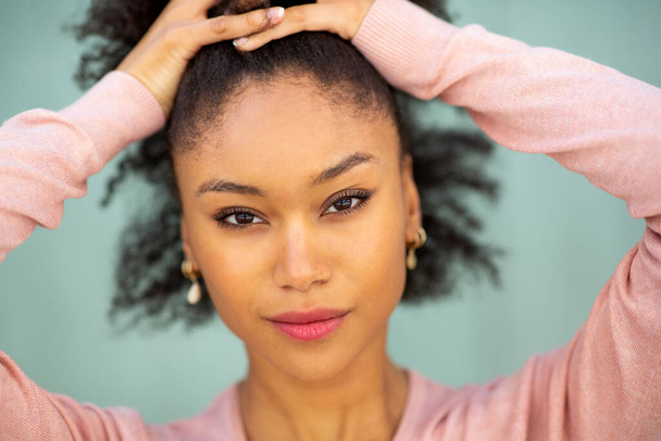 Detail portrét krásná mladá africká americká žena zírá s rukama ve vlasech - Fotografie, Obrázek