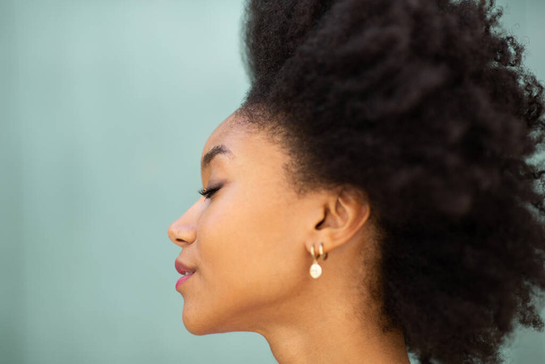 Nahaufnahme Profil Porträt schöne junge afrikanisch-amerikanische Frau mit Afro-Haaren und Augen geschlossen von grünem Hintergrund - Foto, Bild