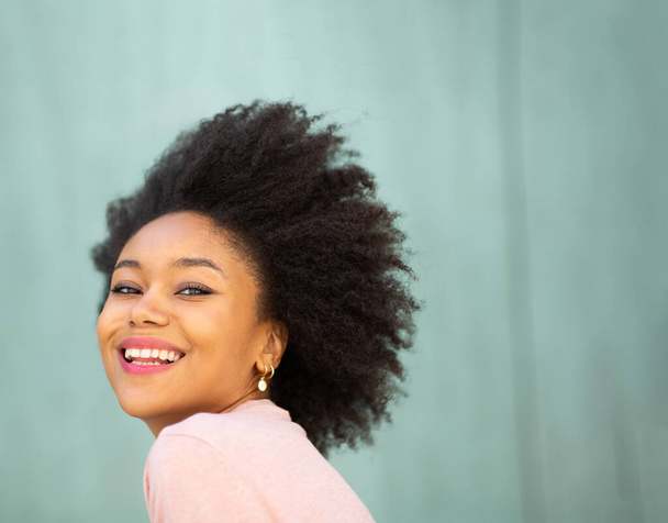 Nahaufnahme Porträt schöne junge schwarze Frau mit Afrohaaren lächelnd vor grünem Hintergrund  - Foto, Bild