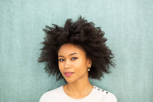 Közelkép portré gyönyörű fiatal afro-amerikai nő afro haj zöld háttér  - Fotó, kép