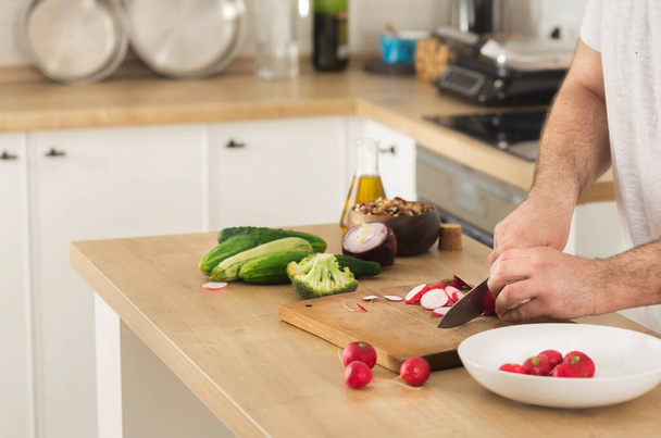 Cooking at home concept Man slices fresh vegetables for cooking vegetarian healthy food - Fotografie, Obrázek
