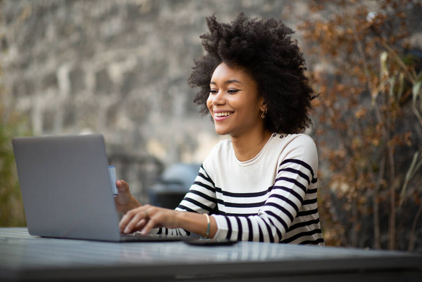 ポートレート笑顔若いアフリカ系アメリカ人女性ラップトップコンピュータを使用して  - 写真・画像