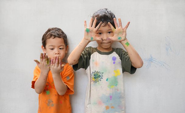 Aranyos kis két ázsiai fiúk testvériség játszani szórakoztató színeket aktivitás kreativitás ideje, mutató folt kéz és ruha. A gyerekeknek szemszínük és sötét barna hajuk van.. - Fotó, kép