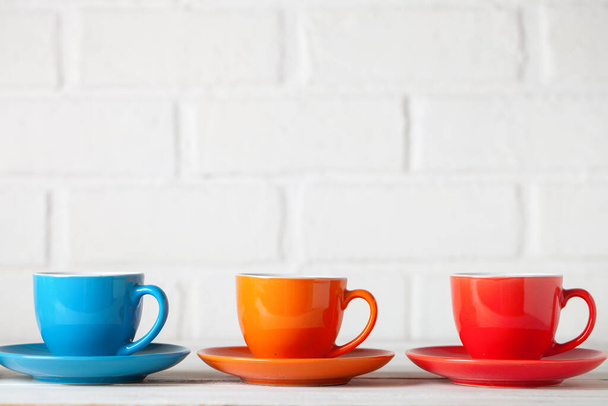 Colorful cups on the white background of a brick wall. Background with copy space. Horizontal. Selective focus. - Foto, Imagen