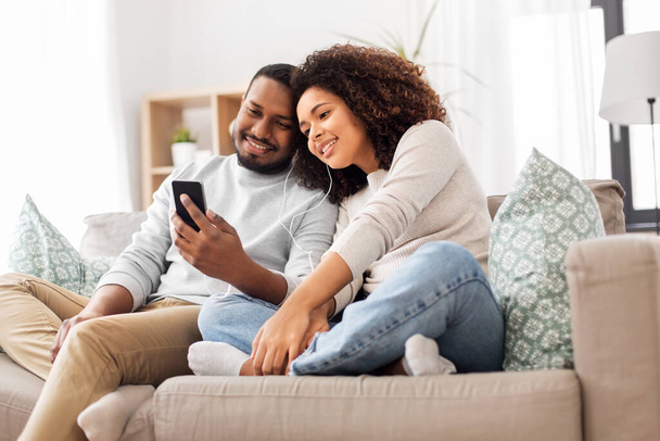 happy couple with smartphone and earphones at home - Foto, imagen