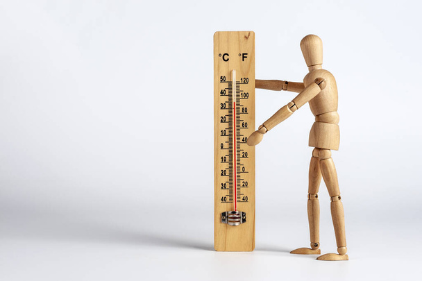 Gorąca letnia pogoda, człowiek z drewna mierzy temperaturę powietrza: termometr skali Celsjusza i Fahrenheita do pomiaru temperatury powietrza. Obiekty odizolowane na białym tle, przestrzeń na tekst. - Zdjęcie, obraz