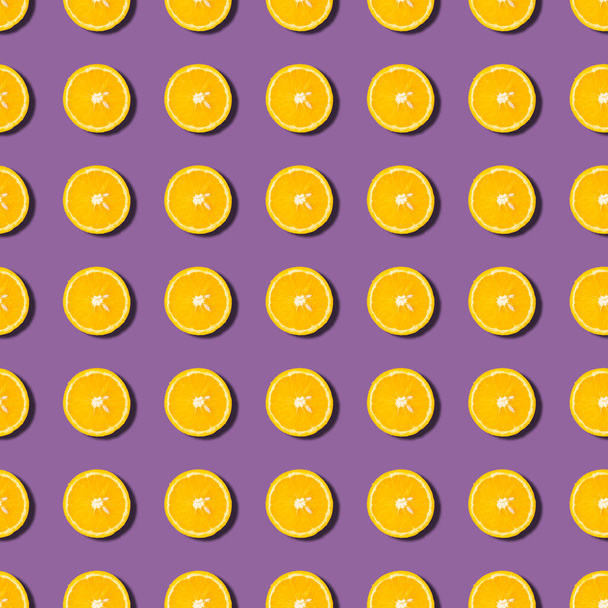 Motif sans couture aux fruits colorés de moitiés orange sur fond violet. Vue du dessus
 - Photo, image