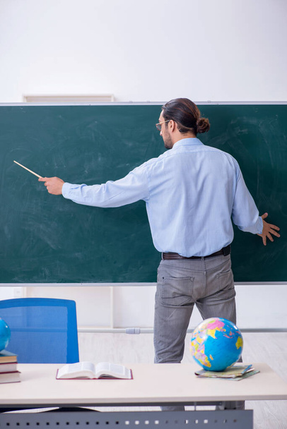Young male geography teacher in front of blackboard - Foto, Imagen