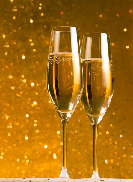 ein Paar Flöten aus Champagner auf goldenem abstrakten Hintergrund - Foto, Bild