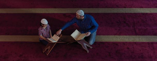 muslim prayer father and son in mosque praying and reading holly book quran together islamic education concept - Foto, Imagem