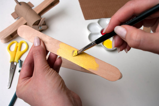 How to make airplane. Hand made toy,zero waste from toilet paper roll and popsicle sticks. For kids and parents. Step 9, wings details paint in yellow. DIY for child, ideas to make during quarantine. - Fotoğraf, Görsel