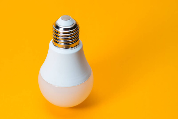 LED, Нова технологічна лампа на жовтому фоні, Енергозберігаюча електрична лампа добре підходить для навколишнього середовища
. - Фото, зображення