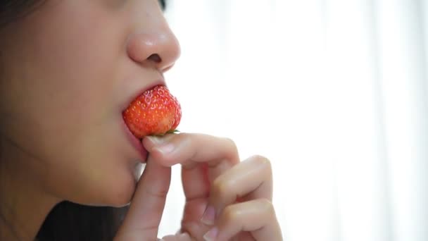 Ασιάτισσα όμορφη γυναίκα κρατώντας και τρώγοντας φρέσκια φράουλα είναι κόκκινο μούρο χρώμα φρούτων και γλυκό ζουμερό με απολαύσετε και χαρούμενη συγκίνηση στην έννοια των τροφίμων, υγιεινό φαγητό στη ζωή - Πλάνα, βίντεο
