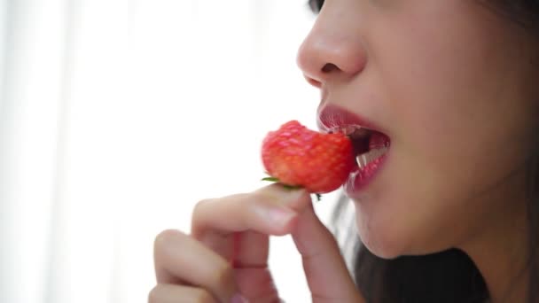 Asian pretty woman holding and eating fresh strawberry is red berry fruit color and sweet juicy with enjoy and happy emotion in concept food, healthy eating in life (Slow motion) - Кадры, видео