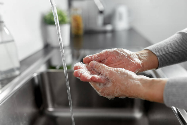 femme se laver les mains avec du savon liquide dans la cuisine - Photo, image