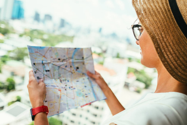 Összezavarodott nő úticél térképpel, városnézést keres - Fotó, kép