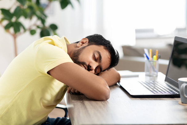 indian man sleeping on table with laptop at home - Foto, afbeelding
