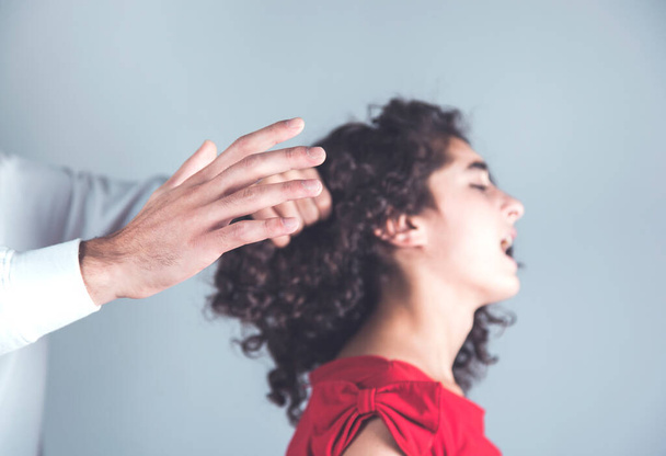 man hand hair beating woman on gray background - Valokuva, kuva