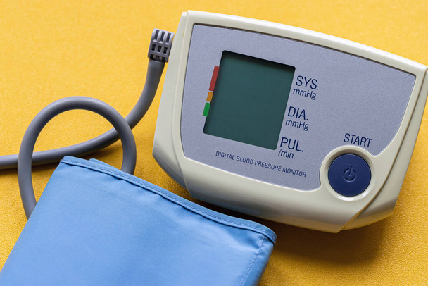 moderno tonómetro electrónico médico sobre un fondo amarillo brillante
. - Foto, imagen