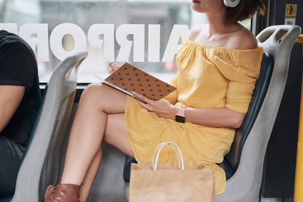 Beautiful young woman sitting in city bus and writing some notes in notebook. - Foto, Imagen