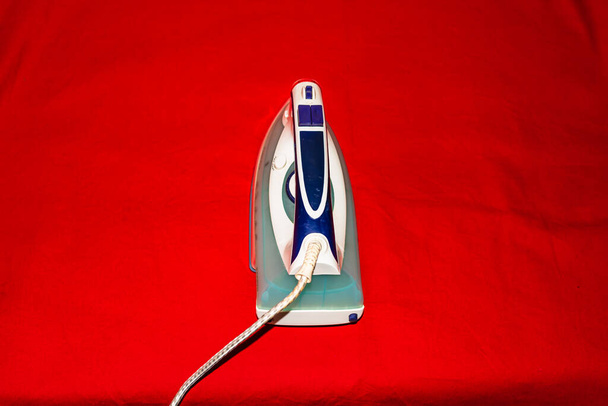 Close-up van een elektrisch strijkijzer geïsoleerd met kopieerruimte. Huishoudelijke wasgoed strijken. - Foto, afbeelding