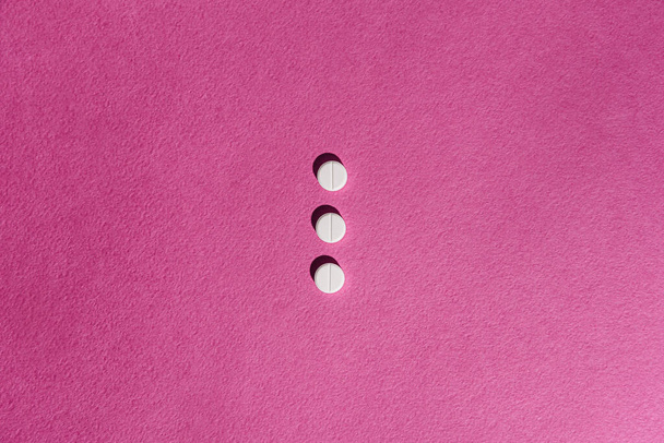 white pills on pink background - Фото, изображение
