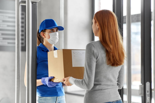 delivery girl in face mask giving parcel to woman - Φωτογραφία, εικόνα