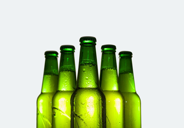 A zöld sörösüvegek egy része kondenzációs cseppekben. Fehér alapon elszigetelve. - Fotó, kép
