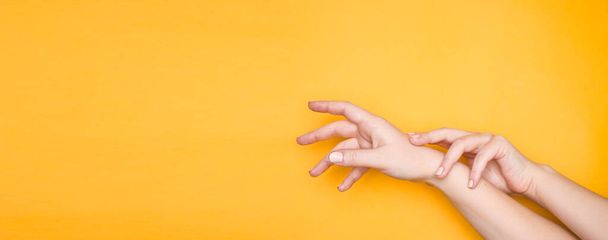 Beautiful female hands reach for something. Yellow background, copyspace. - Photo, Image