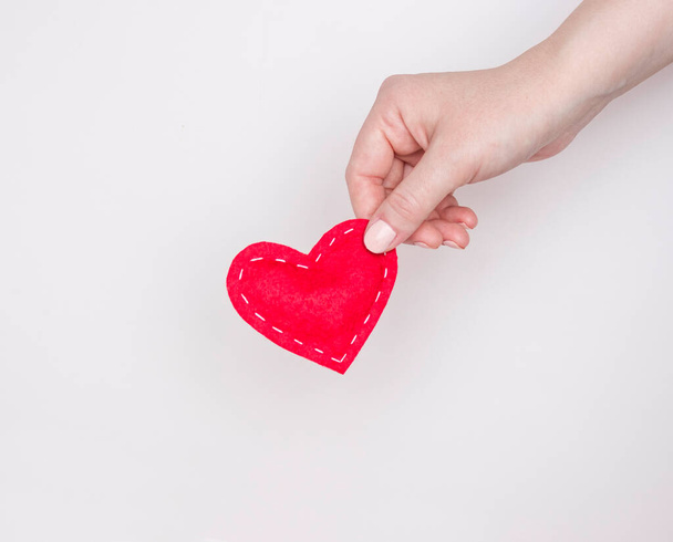 Aşk kavramı, kalp tedavisi. Bir kadının eli kırmızı bir kalbi tutuyor. Hafif arkaplan. - Fotoğraf, Görsel