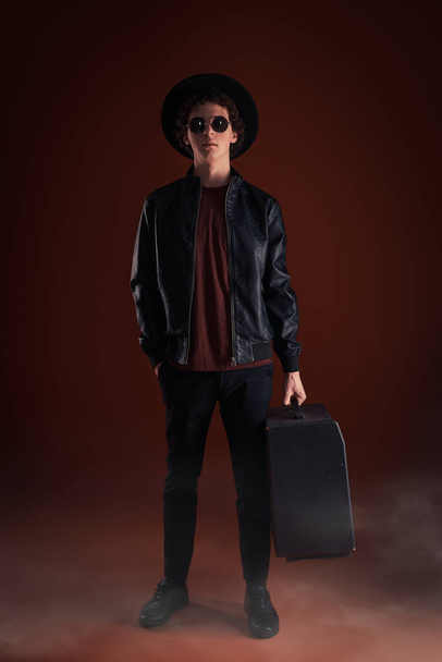 cara jovem em óculos e um chapéu com uma coluna de música no estúdio
  - Foto, Imagem