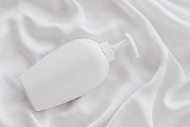 Blank label cosmetic container bottle as product mockup on white silk background - Photo, Image