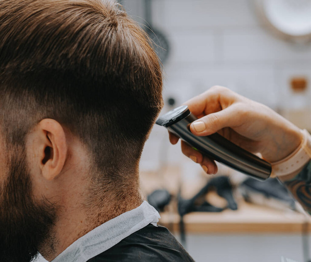 Mens haircut at home. The hairdresser cuts the hair of a man - Φωτογραφία, εικόνα