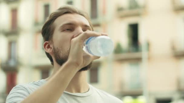 Młody Thisty Man pije i cieszy się butelką zimnej wody - Materiał filmowy, wideo