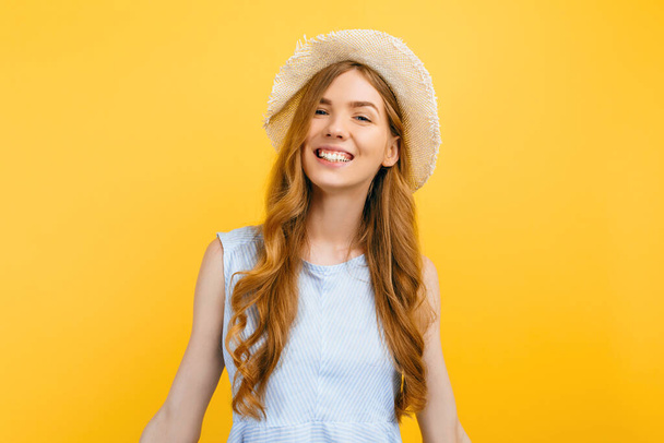 Portrait of a cheerful young girl in a summer hat, dressed in summer clothes, smiling on an isolated yellow background - Фото, зображення