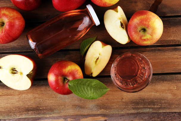 Apple cider drink and apples with leaves on rustic table - Photo, image