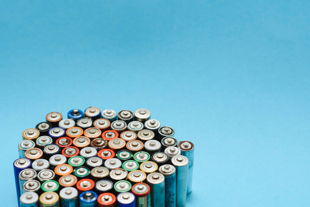 Close up of positive ends of colorful discharged batteries of different sizes and formats, top view, copy space. Used alkaline battery on concrete background. Hazardous garbage concept. - Fotografie, Obrázek