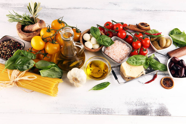 Italienische Küche mit Kräutern und Gewürzen, Weintomaten, Basilikum, Spaghetti, Oliven, Parmesan, Olivenöl, Knoblauch, Pfefferkörnern und Rosmarin - Foto, Bild