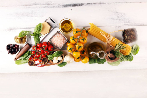 Ιταλική κουζίνα με βότανα και μπαχαρικά, ντομάτες αμπέλου, βασιλικό, σπαγγέτι, ελιές, παρμεζάνα, ελαιόλαδο, σκόρδο, πιπεριές και δεντρολίβανο - Φωτογραφία, εικόνα