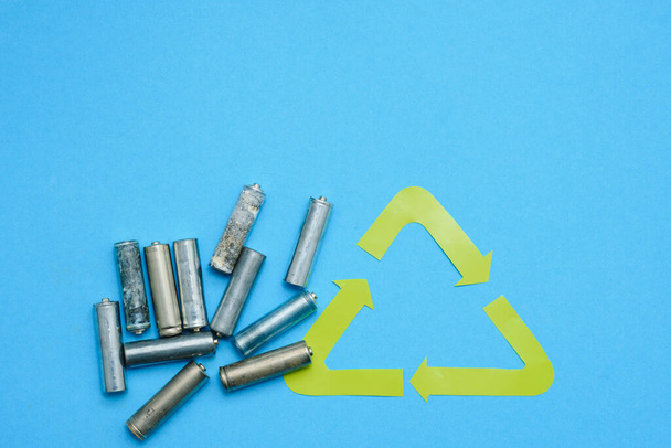 Use AA and properly dispose of batteries that are toxic to the environment and soil against a green background. The concept of technologies for processing hazardous and recyclable substances. - Foto, Bild