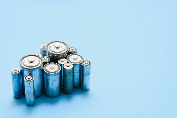Scattered old dirty batteries aa or aaa size on blue background. Recycling concept. Save environment. Alternative energy - Fotografie, Obrázek