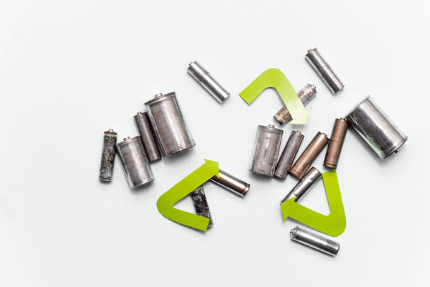 Use AA and properly dispose of batteries that are toxic to the environment and soil against a green background. The concept of technologies for processing hazardous and recyclable substances. - Zdjęcie, obraz