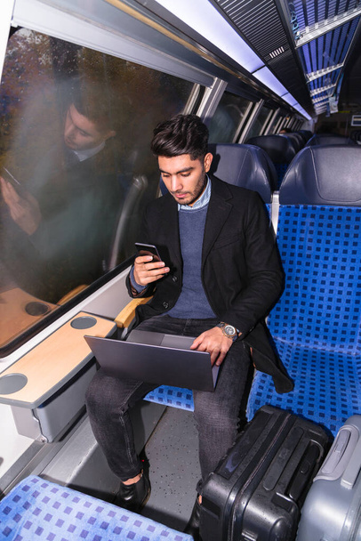 Businessman working with laptop on way in train - Foto, imagen