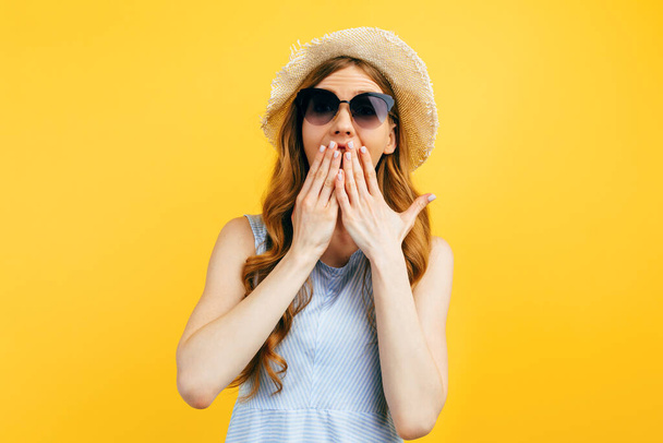 Shocked surprised girl in sunglasses and a summer hat, on a yellow background. Travel, vacation, summer - Foto, Imagem
