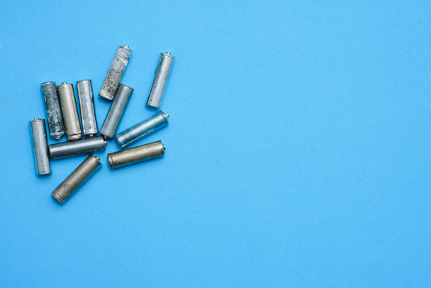 many used AA batteries on a blue background. - Photo, Image