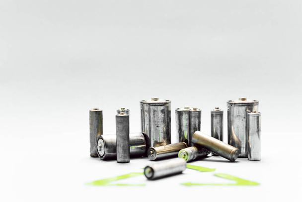 waste recycling, garbage disposal, environment and ecology concept - close up of used alkaline batteries and green recycling symbol - Fotoğraf, Görsel