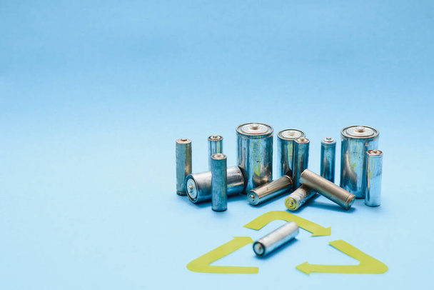 Use AA and properly dispose of batteries that are toxic to the environment and soil against a green background. The concept of technologies for processing hazardous and recyclable substances. - Foto, imagen