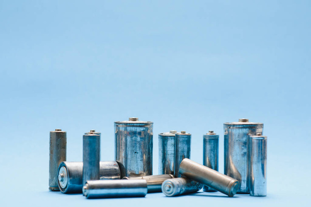 many used AA batteries on a blue background. - Foto, Bild