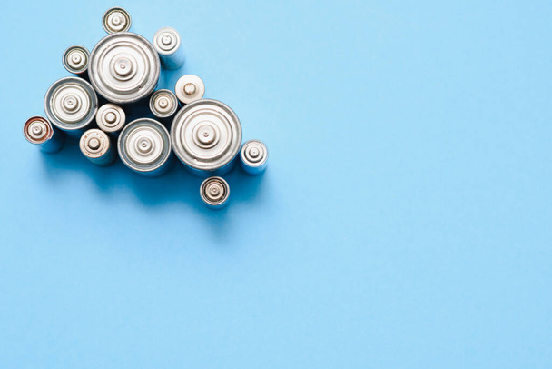 many used AA batteries on a blue background. - Фото, изображение
